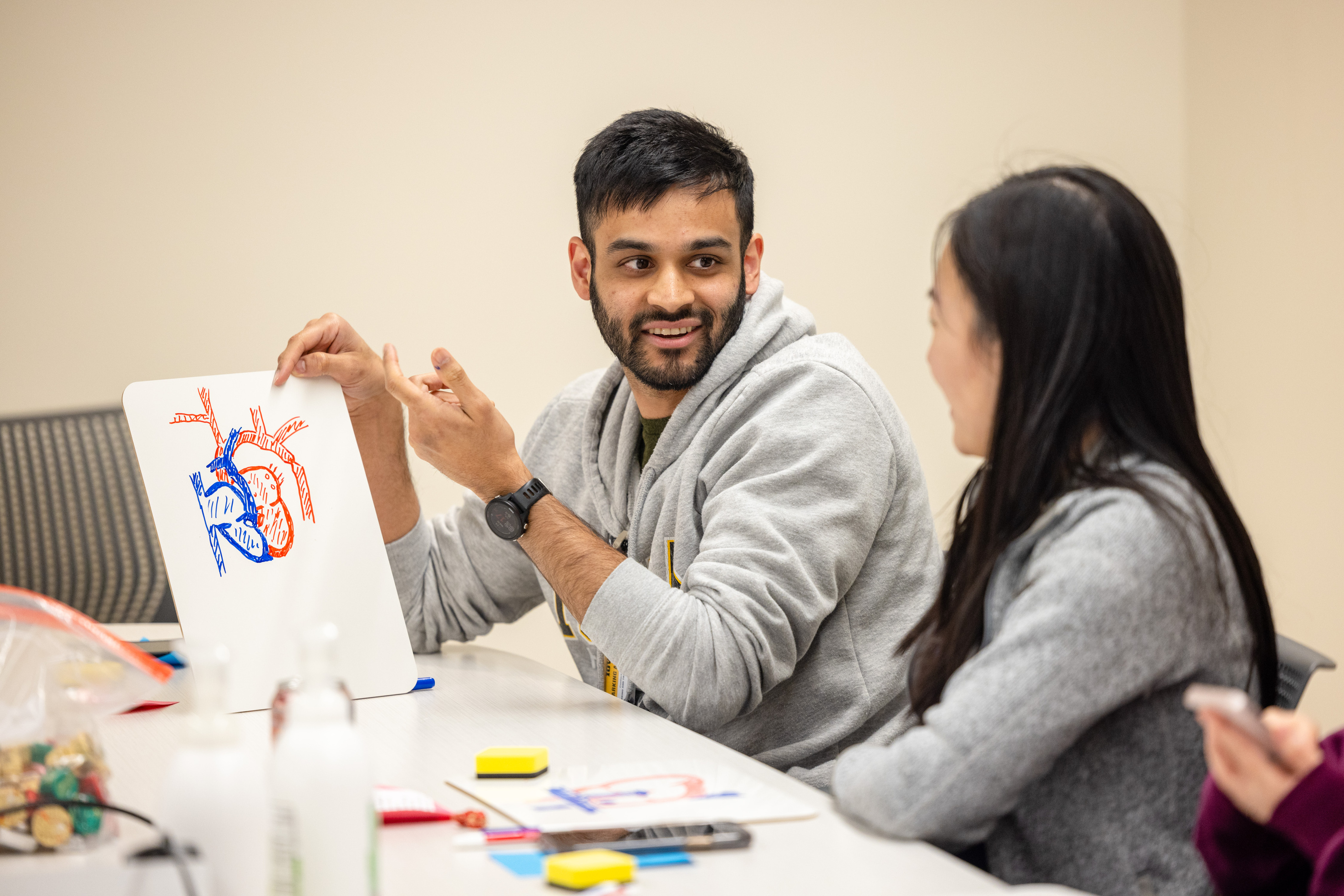 Pediatric residents review the anatomy of a heart drawn on a dry erase board. 