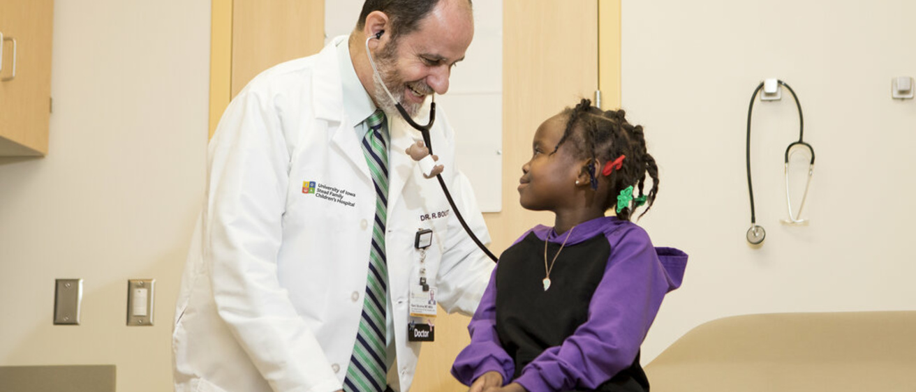A child smiles as she is examined by a University of Iowa Health Care doctor.